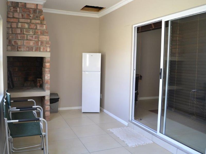 Covered patio area featuring a built-in brick fireplace, tiled flooring, and sliding glass doors leading to the interior.