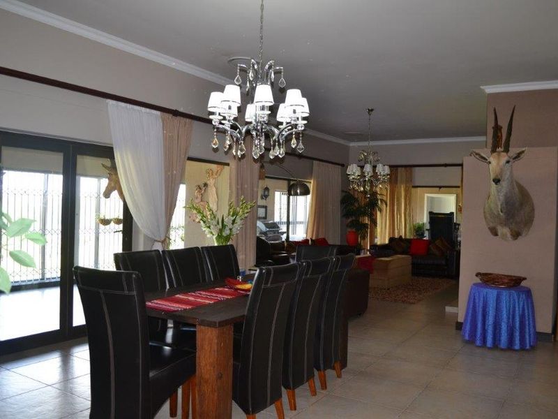Spacious open-plan living and dining area featuring tiled floors, elegant crystal chandeliers, and large sliding glass doors providing access to the exterior.