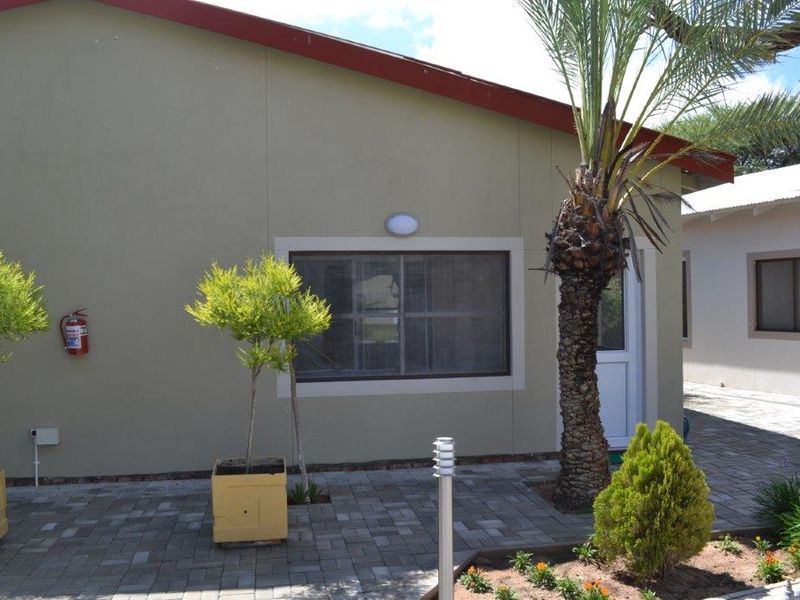 A view of the exterior rear facade featuring paved patio area, external lighting, and a secure entrance door.