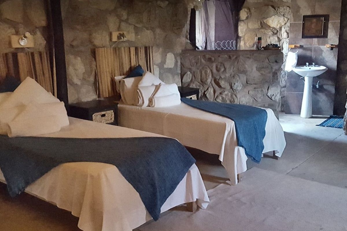 Rustic bedroom featuring natural stone walls and an integrated pedestal basin, offering a unique and textured interior aesthetic.