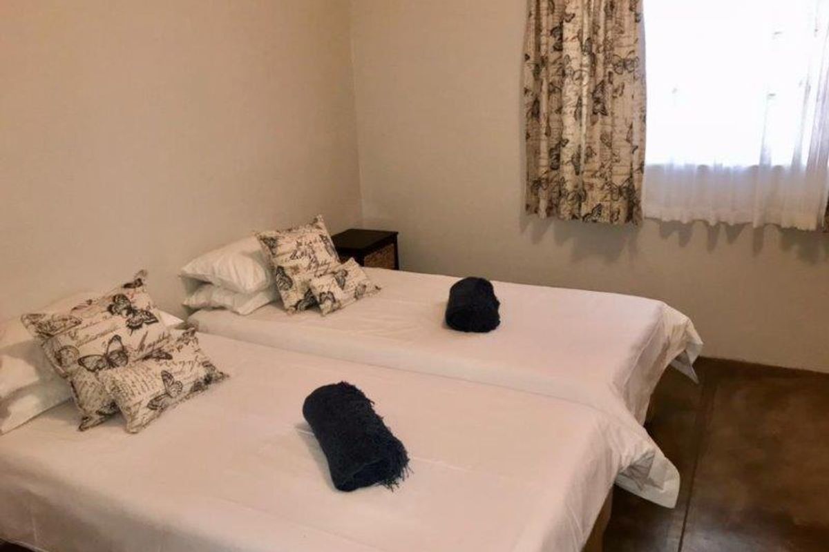 A bedroom featuring tiled flooring and a window with curtains, providing a functional and simple sleeping space.
