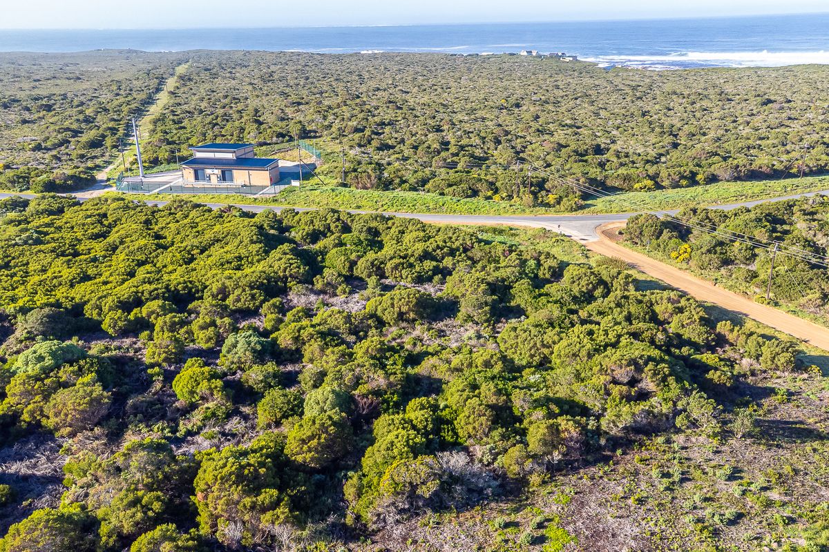 Aerial view of a commercial vacant land plot featuring a utility building, access roads, and coastal landscape surroundings.