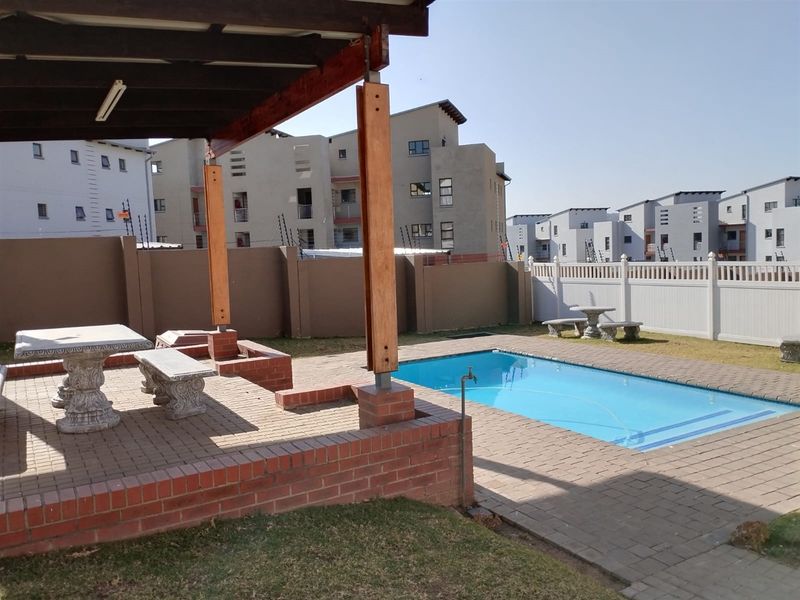 Outdoor pool area featuring a paved patio, timber pergola structure, and a swimming pool enclosed by perimeter walls and fencing.