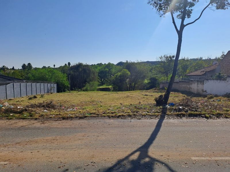 A vacant residential plot featuring a boundary wall and street frontage, offering a clear space for future development.