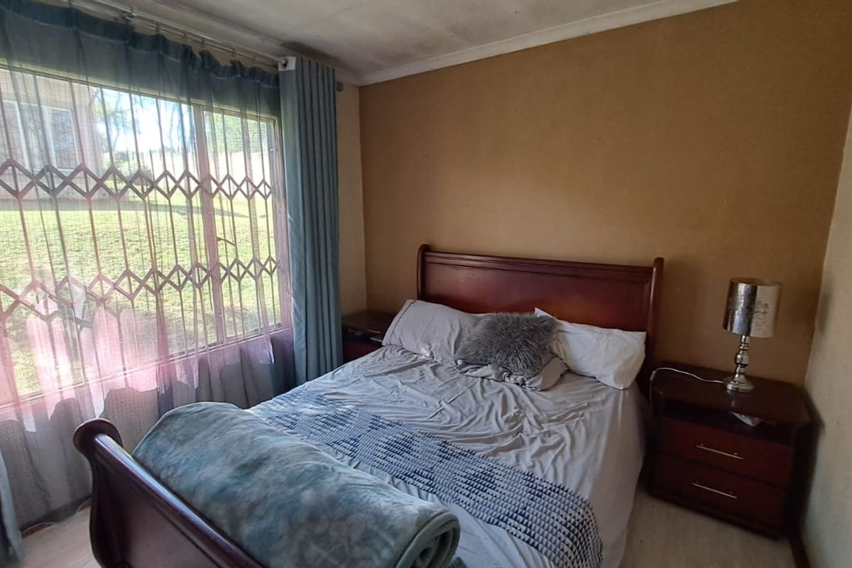 A bedroom featuring a large window with a security gate, neutral wall tones, and coving detail, requiring cosmetic updates to improve the overall finish.