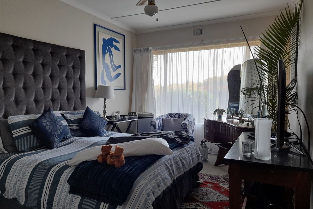 A well-lit bedroom featuring a ceiling fan and a large window that allows for ample natural light.