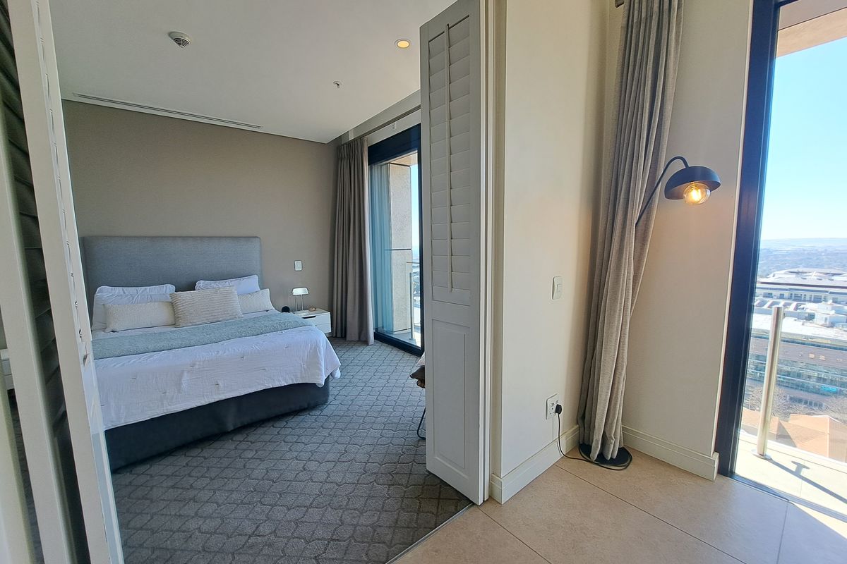 A well-maintained bedroom featuring carpeted flooring, recessed lighting, and large sliding glass doors leading to a balcony, providing ample natural light.