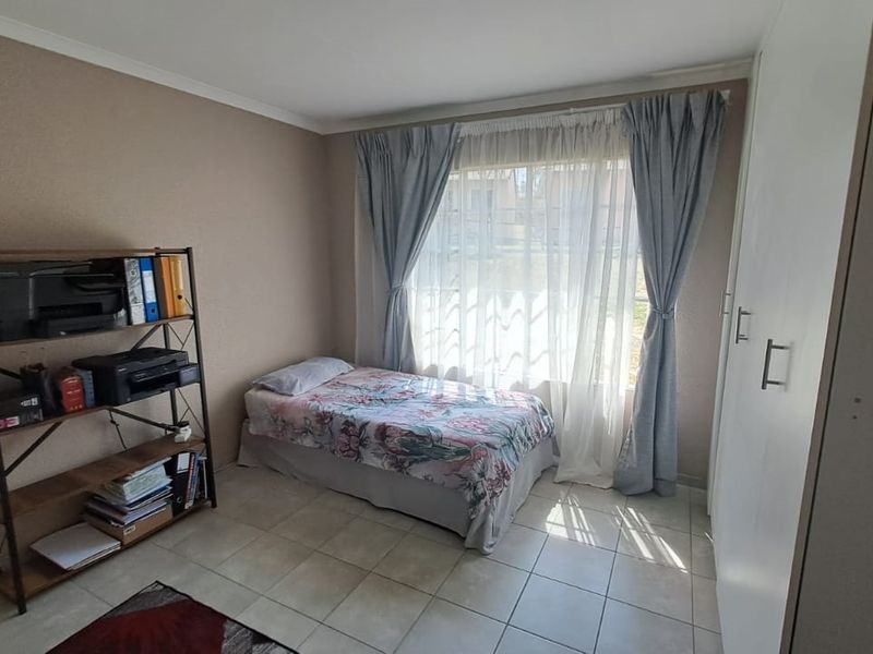 A functional bedroom featuring tiled flooring and a built-in wardrobe, offering a neutral space ready for personalization.