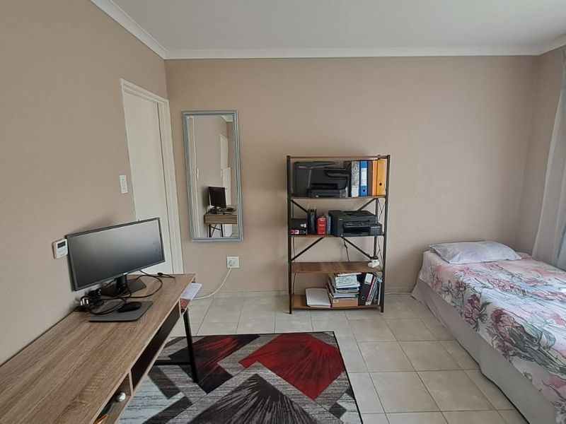 A functional bedroom featuring tiled flooring and neutral wall tones, offering a versatile space suitable for a bedroom or home office setup.