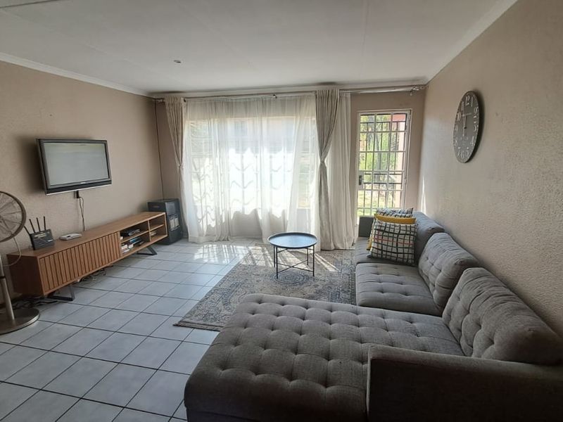 A living room featuring tiled flooring, coved ceilings, and a security gate leading to the exterior.