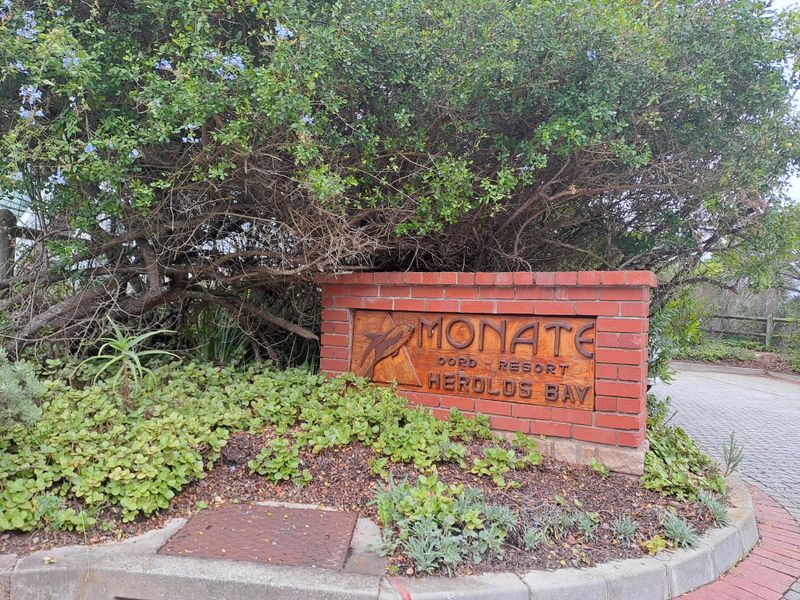 Entrance signage for Monate Resort in Herolds Bay, featuring a brick wall structure set within a landscaped garden area.