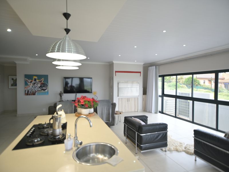 Spacious open-plan living area featuring a modern kitchen island with gas hob, sleek cabinetry, and large sliding doors providing ample natural light.