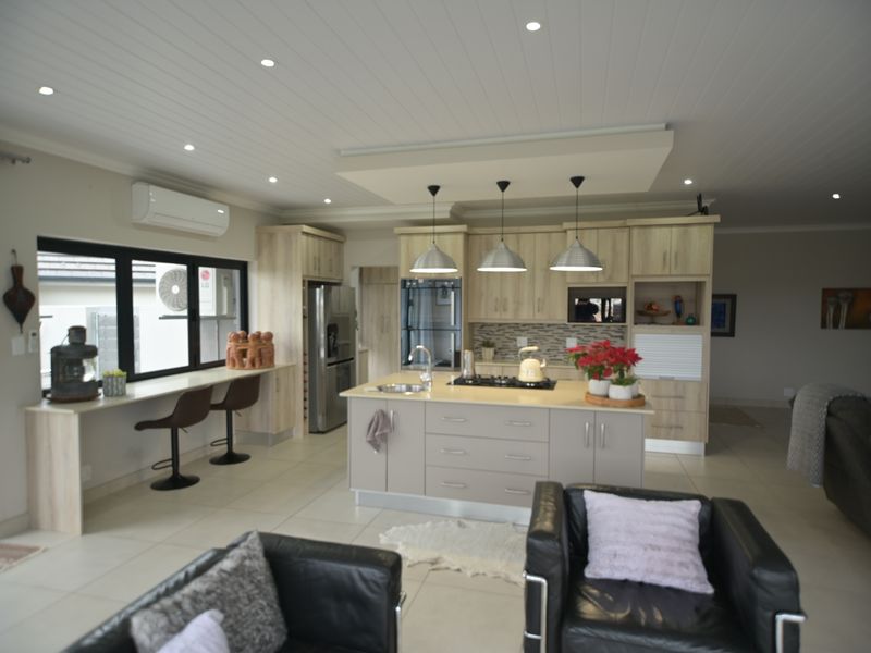 Spacious open-plan kitchen and living area featuring a central island, modern cabinetry, recessed lighting, and a breakfast bar overlooking the living space.