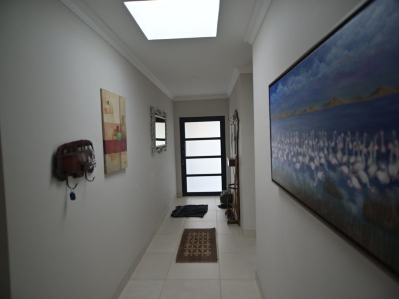 A bright and welcoming hallway featuring tiled flooring, a modern front door, and a skylight that provides ample natural light.