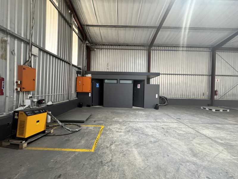 Spacious industrial warehouse unit featuring high ceilings, concrete flooring, corrugated metal walls, and a dedicated internal restroom block with electrical infrastructure.
