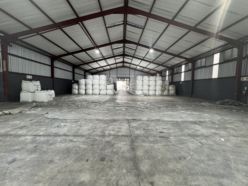 Spacious industrial warehouse featuring a steel portal frame structure, concrete flooring, and high-clearance ceilings with integrated skylights and industrial lighting.