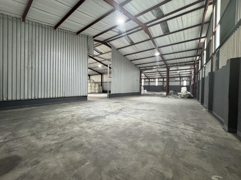 Spacious industrial warehouse featuring high ceilings, exposed steel portal frame construction, corrugated metal walls, and durable concrete flooring.