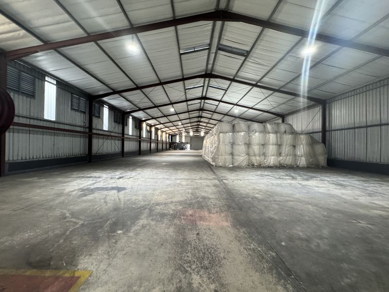 Spacious industrial warehouse featuring a steel portal frame, concrete flooring, and natural light through roof skylights, suitable for storage or manufacturing operations.
