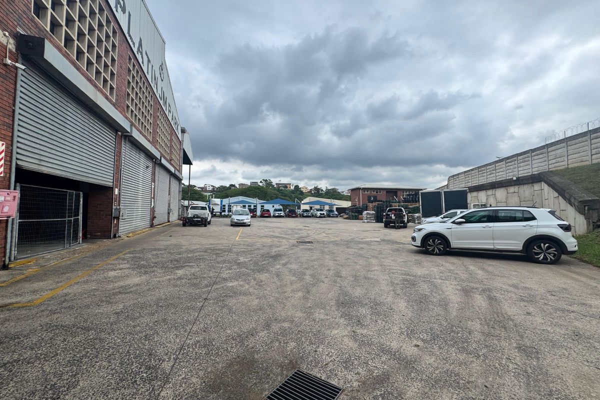 Spacious industrial yard area featuring concrete paving, large roller shutter doors, and perimeter security walling, suitable for logistics or commercial operations.