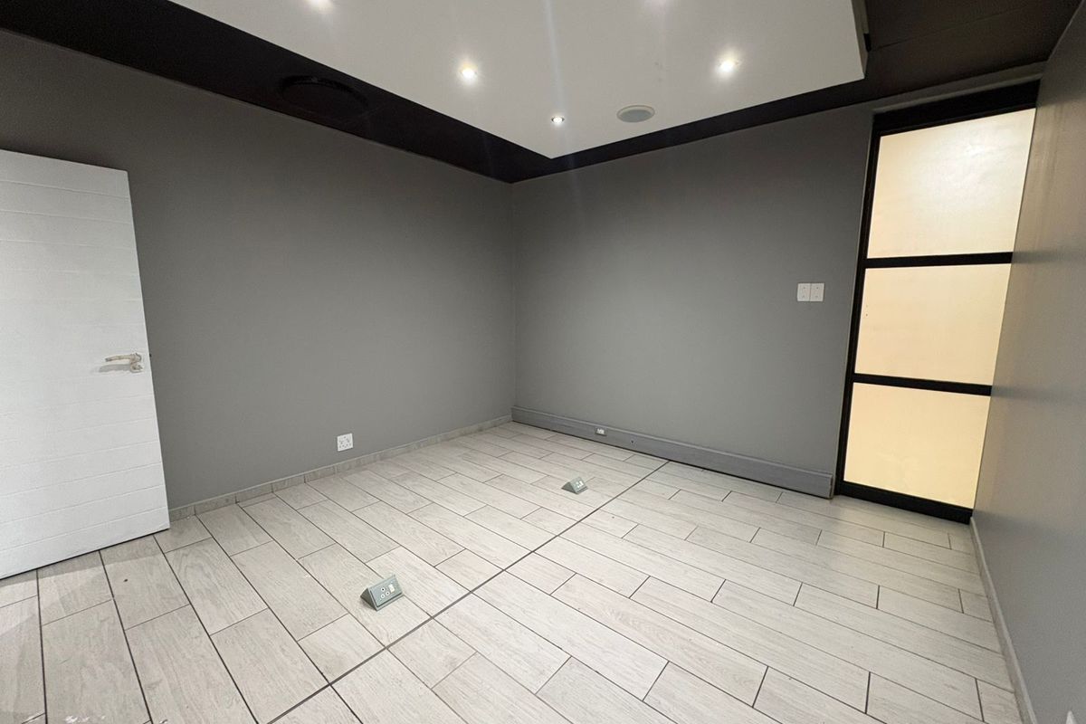 A modern, empty room featuring tiled flooring, recessed ceiling lighting, and a contemporary glass-paneled door, suitable for use as a bedroom or office space.
