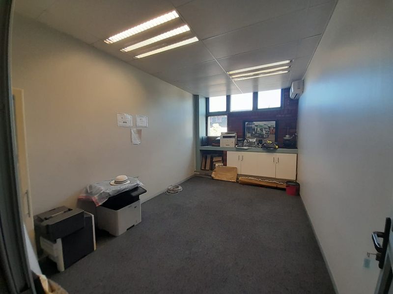 A functional office space featuring built-in cabinetry, suspended ceiling with integrated lighting, and an air conditioning unit.