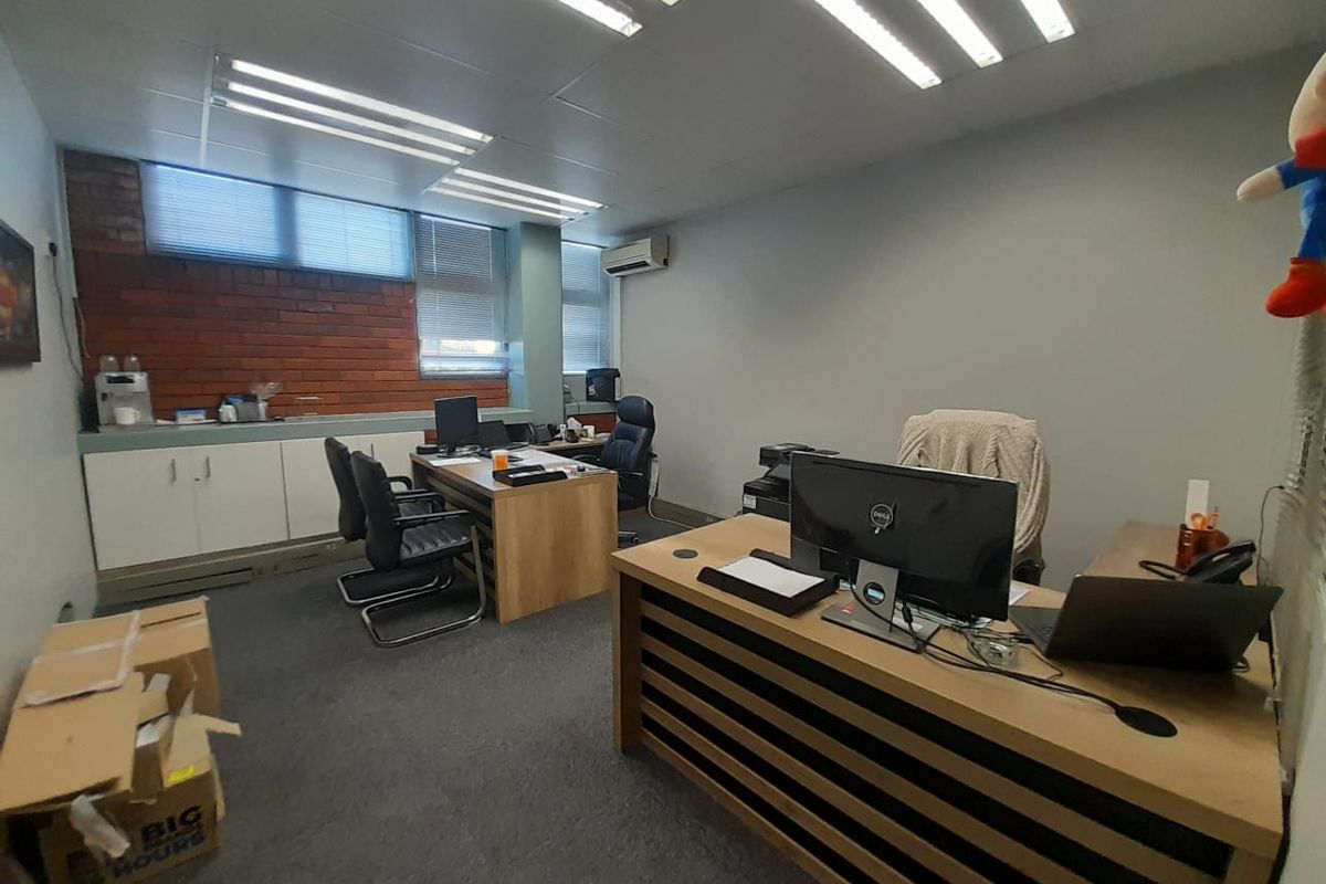 Functional office space featuring built-in cabinetry, exposed brick accents, carpeted flooring, and integrated air conditioning, suitable for professional use.