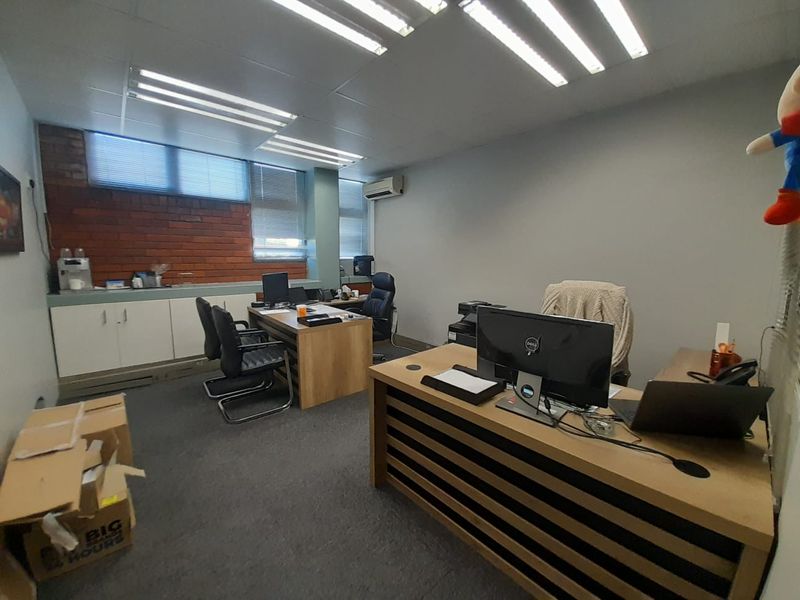 Functional office space featuring built-in cabinetry, exposed brick accents, carpeted flooring, and integrated air conditioning, suitable for professional use.