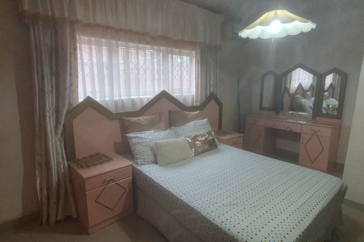 A bedroom featuring a window with security gate and an installed air conditioning unit.