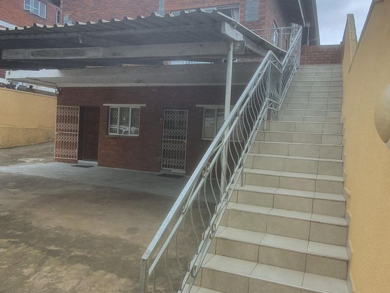 Exterior view of the property featuring a tiled staircase with metal balustrade leading to the upper level and a covered carport area.