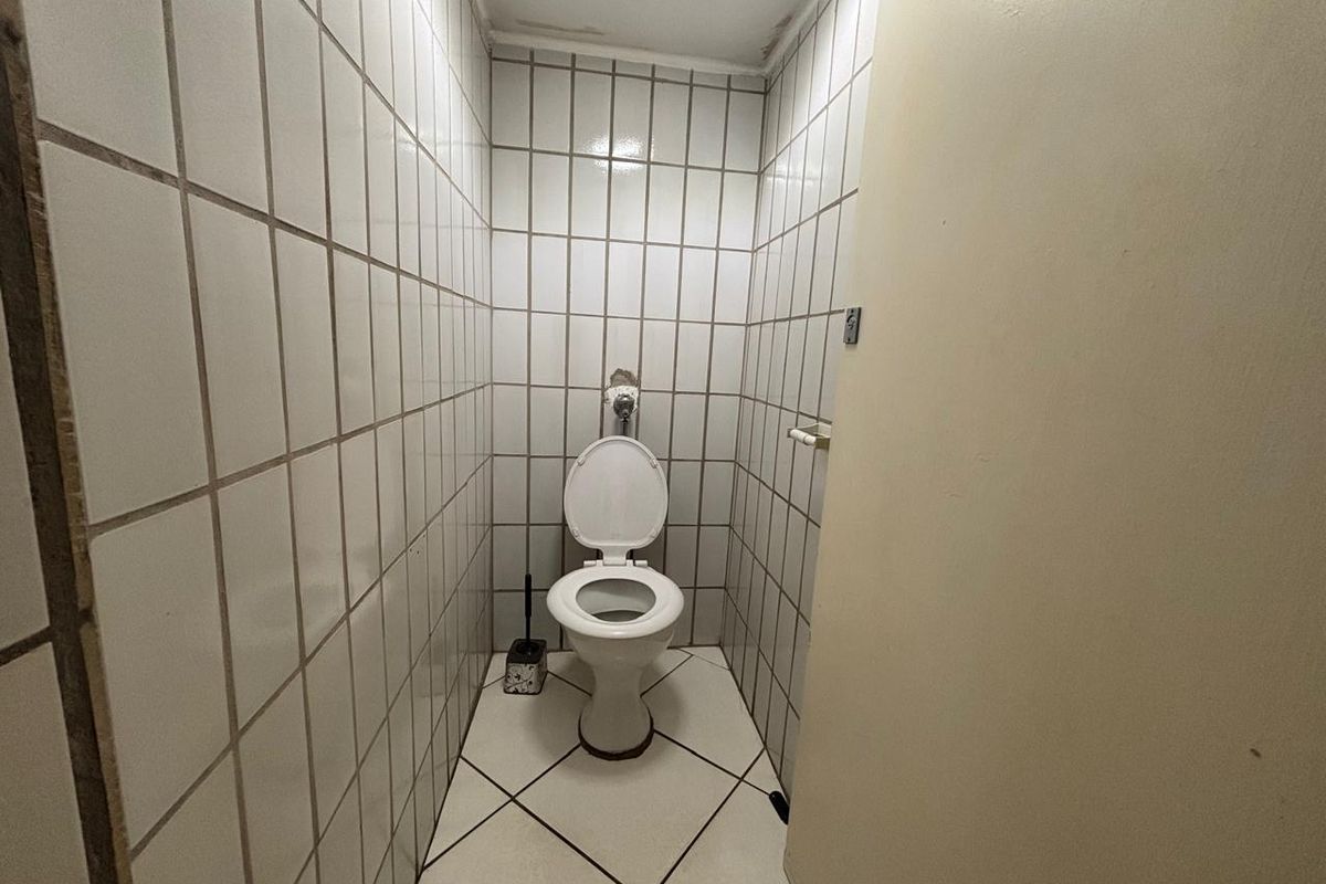 A compact restroom featuring full-height wall tiling, a standard toilet suite, and tiled flooring.