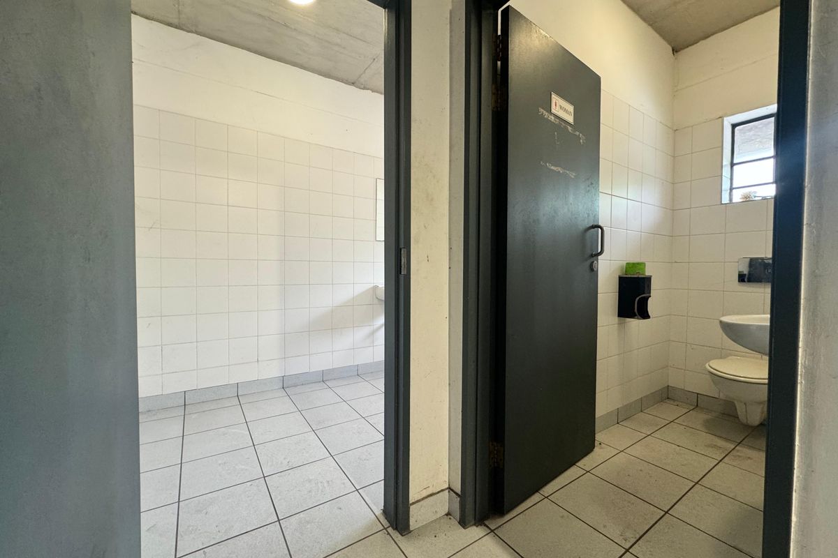 Functional industrial restroom facility featuring tiled walls and floors with separate cubicle access.