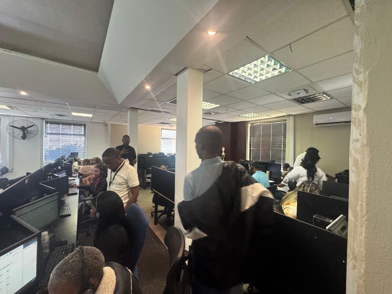 A functional open-plan office space featuring a drop ceiling with integrated lighting, air conditioning unit, and multiple workstation configurations.