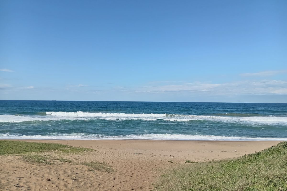 A scenic view of the ocean and sandy beach, showcasing the natural landscape and coastal frontage of the property.