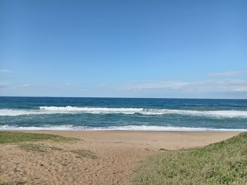 A scenic view of the ocean and sandy beach, showcasing the natural landscape and coastal frontage of the property.
