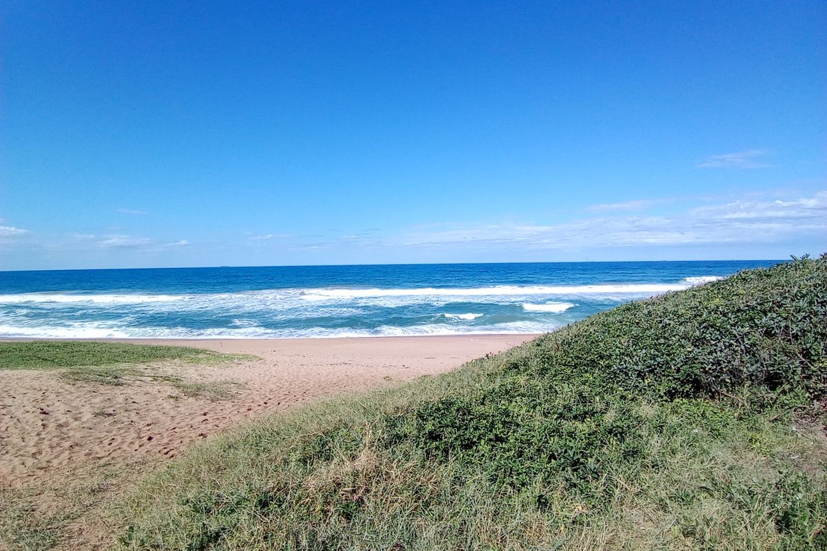 A scenic view of the coastline featuring sandy dunes and the ocean, highlighting the natural landscape of the property.