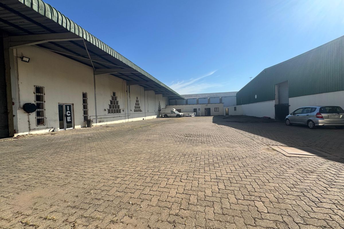 Spacious industrial yard with paved surface, large warehouse structures, and secure perimeter access, suitable for logistics or storage operations.