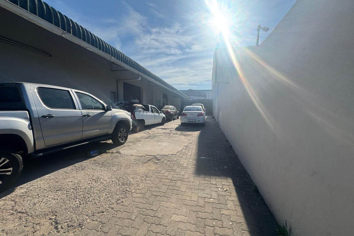 Exterior side access area of the industrial property featuring paved ground and perimeter walling.