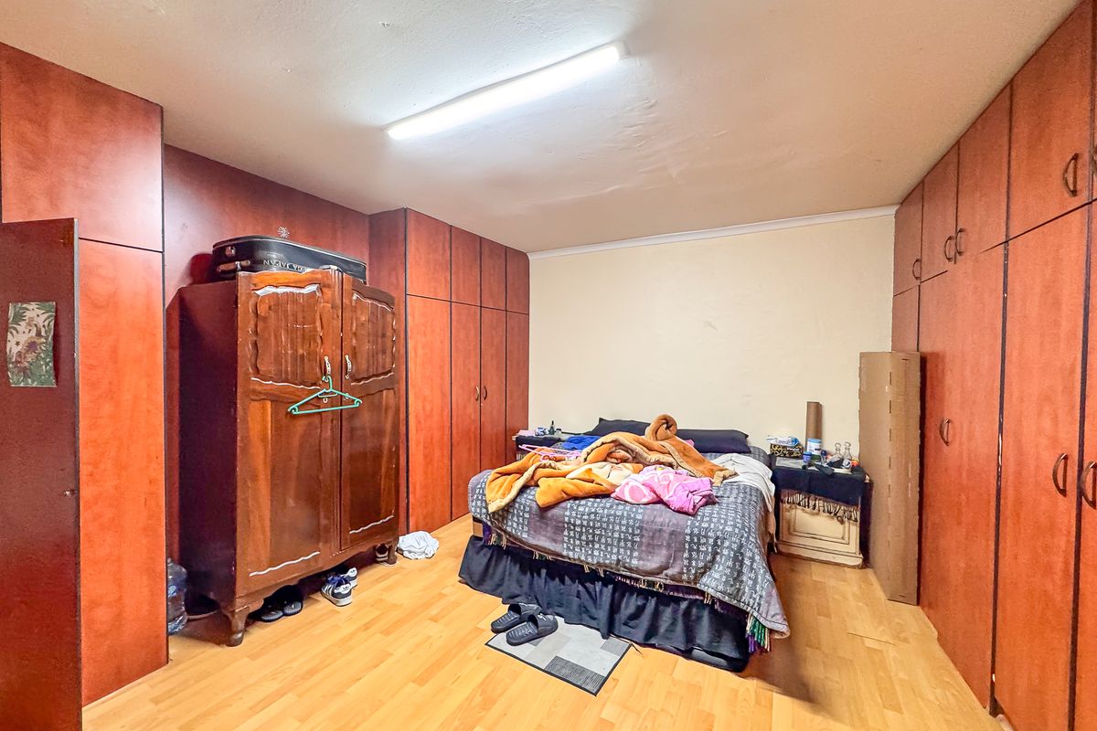 A bedroom featuring extensive built-in wooden cabinetry providing ample storage space, complemented by laminate flooring and a central fluorescent light fixture.