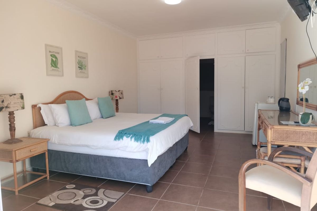 A well-maintained guest bedroom featuring built-in floor-to-ceiling wardrobes, tiled flooring, and direct access to an en-suite bathroom.