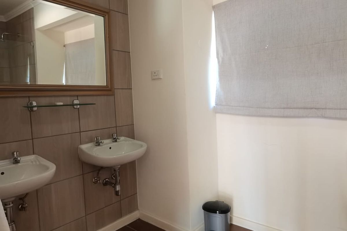 A functional bathroom featuring dual wall-mounted ceramic basins, tiled splashbacks, and a large framed mirror.