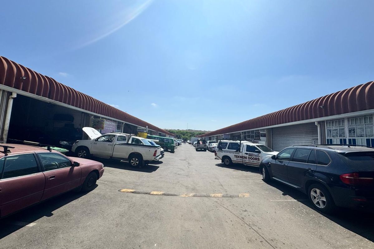 Exterior view of an industrial complex featuring multiple warehouse units with curved roof profiles and paved driveway access.