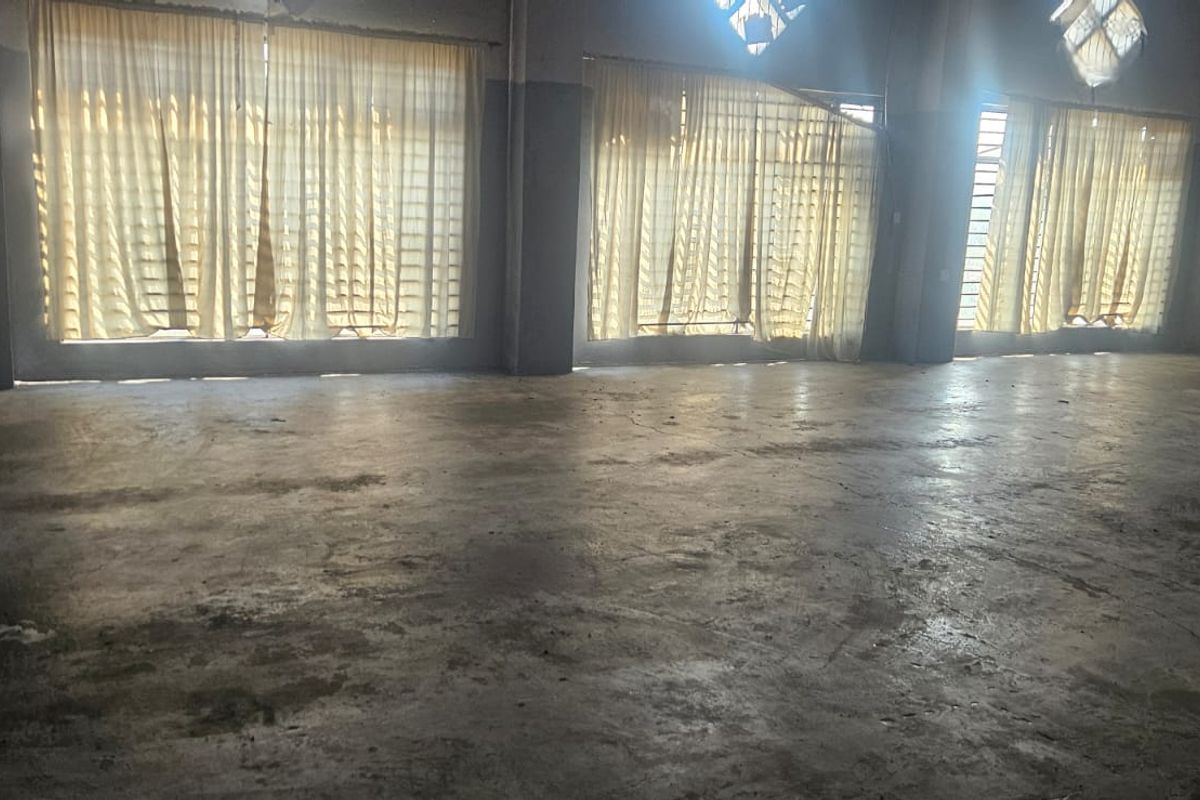 A large, open-plan industrial utility space featuring expansive windows and durable concrete flooring, suitable for various commercial or storage applications.