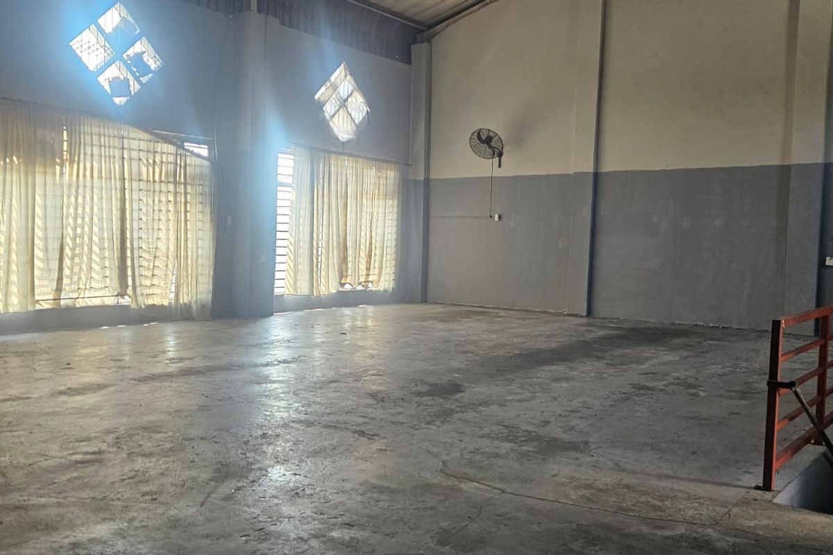 Spacious industrial utility area featuring concrete flooring, high-level windows, and wall-mounted ventilation fans, suitable for warehouse or workshop use.