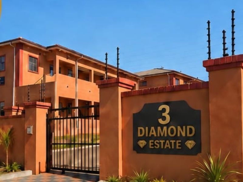 Front entrance view of Diamond Estate featuring a secure gated access point, perimeter wall with electric fencing, and paved driveway.