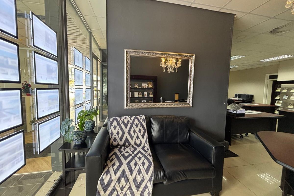 A professional retail office space featuring large glass display windows, tiled flooring, and a modern suspended ceiling with integrated lighting.