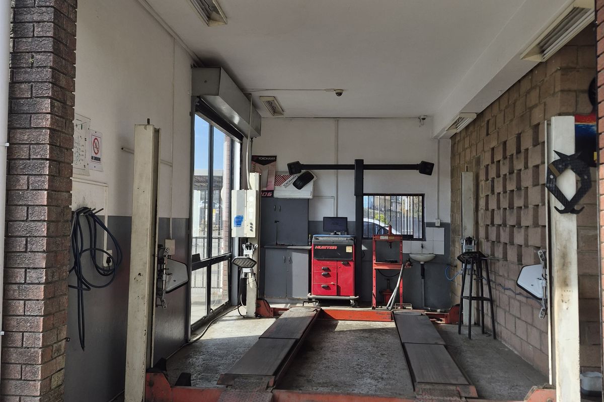 A functional automotive workshop bay featuring a built-in vehicle lift, exposed brick walls, and integrated lighting, suitable for professional mechanical services.