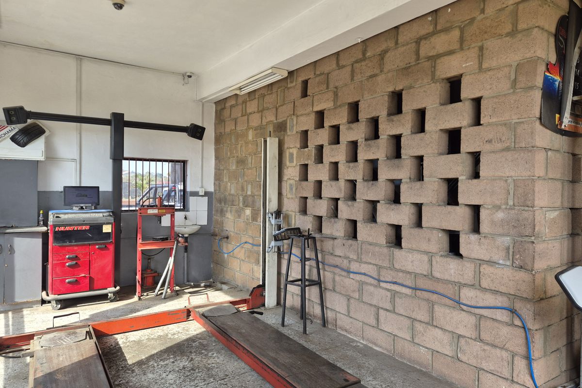 Industrial garage space featuring a vehicle lift, a decorative breeze block wall, and a functional wash basin area.