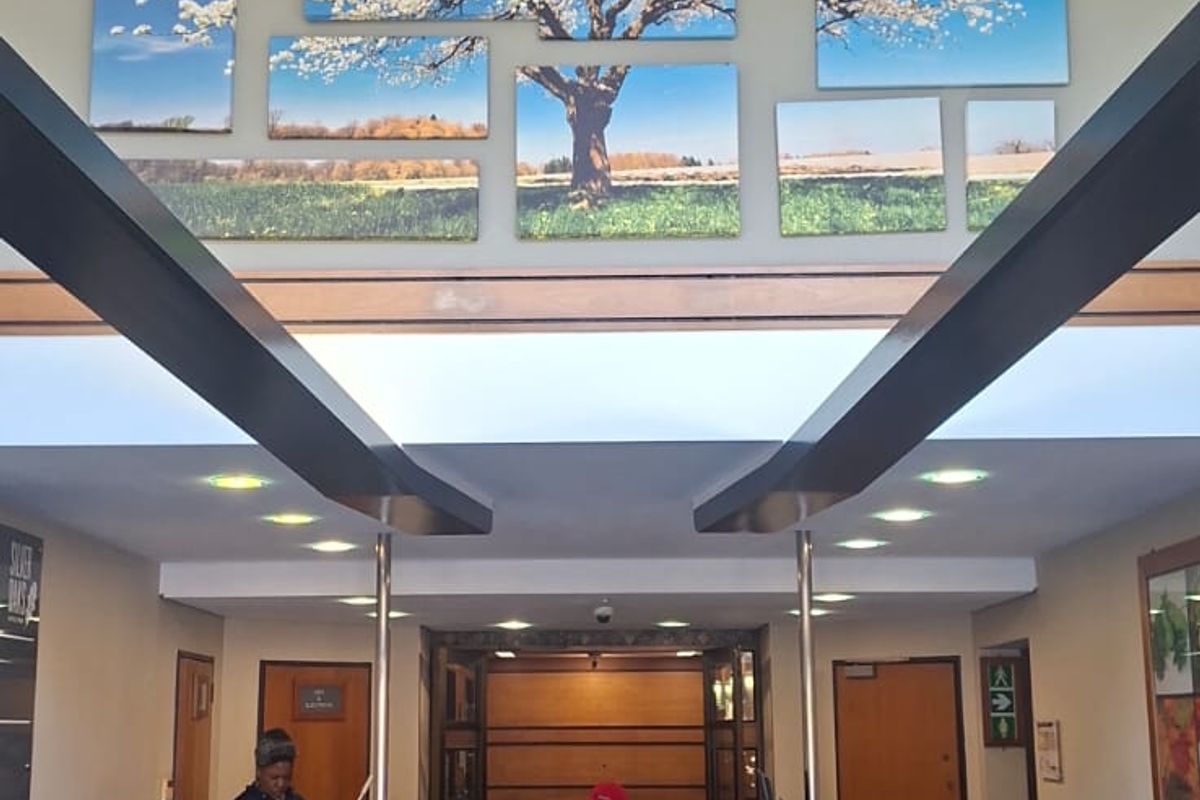 A professional office building entrance featuring a central reception desk, high ceilings with exposed beams, and polished tiled flooring.
