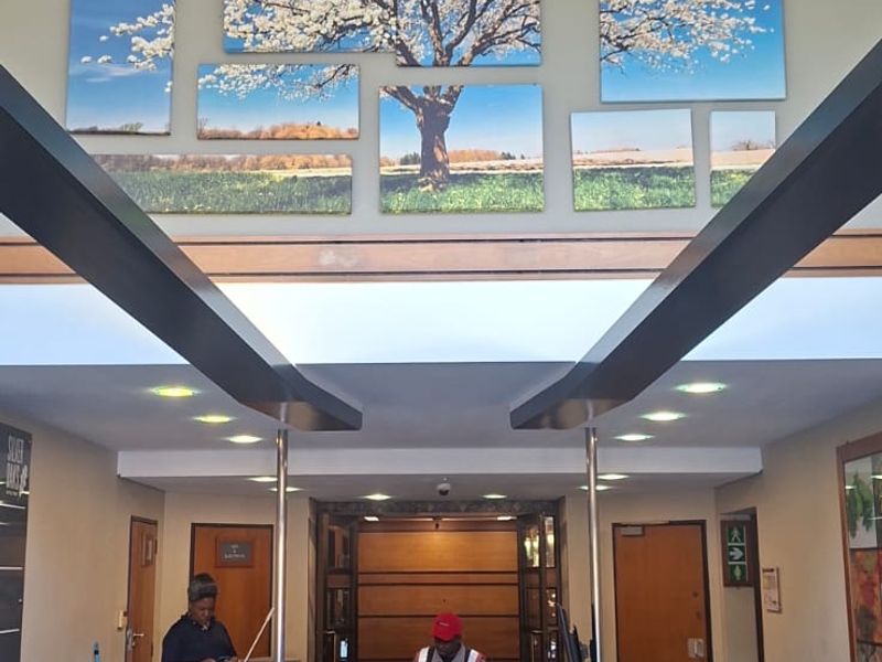 A professional office building entrance featuring a central reception desk, high ceilings with exposed beams, and polished tiled flooring.