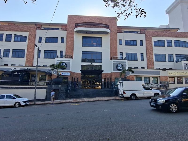 A multi-story commercial office building featuring a brick and plaster facade with large glass windows and a prominent central entrance.